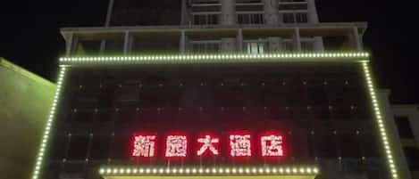 A building with illuminated signage, a prominent entrance, and a vertical light strip.
