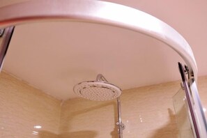 A glass-enclosed shower with a curved ceiling, a handheld showerhead, and a chrome faucet. - Xingdu Hotel (Fangchenggang)