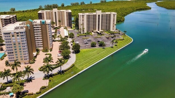 Ein Hochhaus-Hotel mit mehreren Etagen, einem Parkplatz und Blick auf das Wasser.