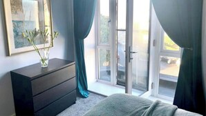 Un dormitorio con un aparador, un cuadro enmarcado y una ventana con cortinas.