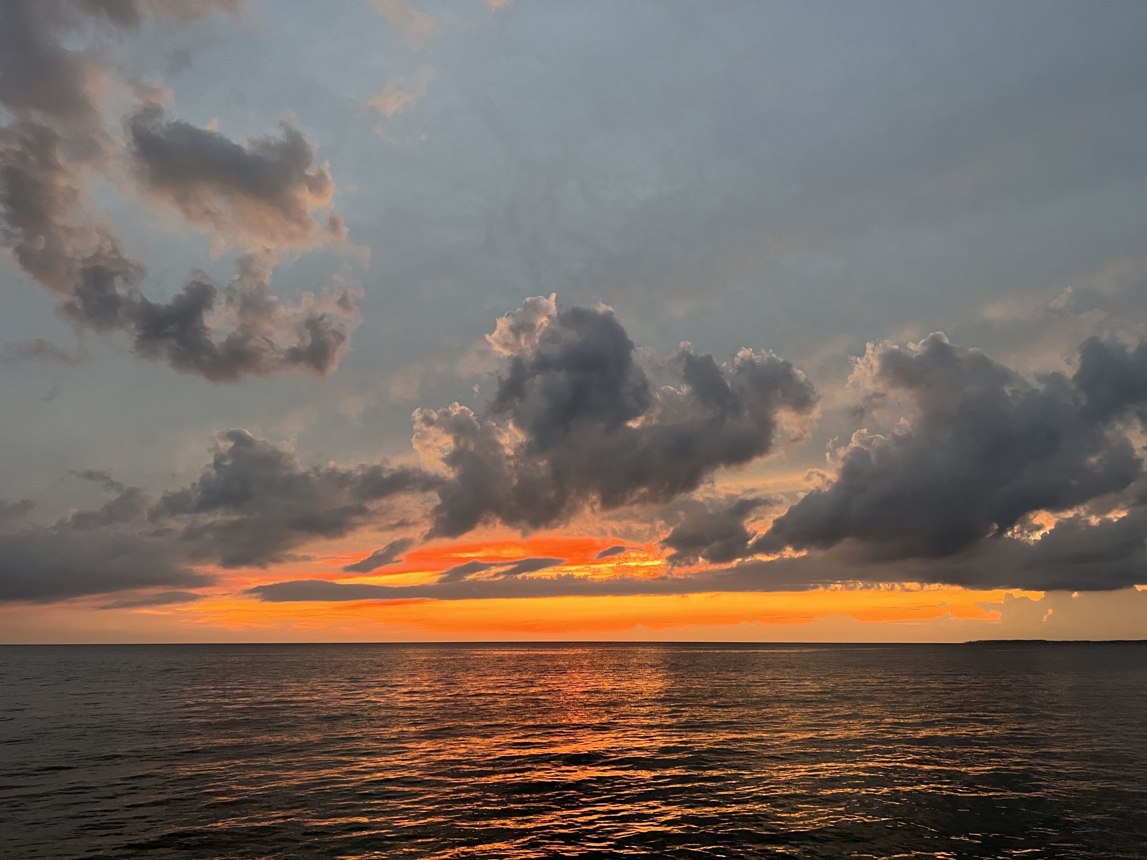 A sunset over a body of water with clouds in the sky.