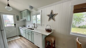 A kitchen with white cabinets, a wooden countertop, a star decoration, and a window with a view of the outdoors. - Waterfront Harbor Home, Sunset Views, Fireplace, Private dock and Boat Slip (Kill Devil Hills)