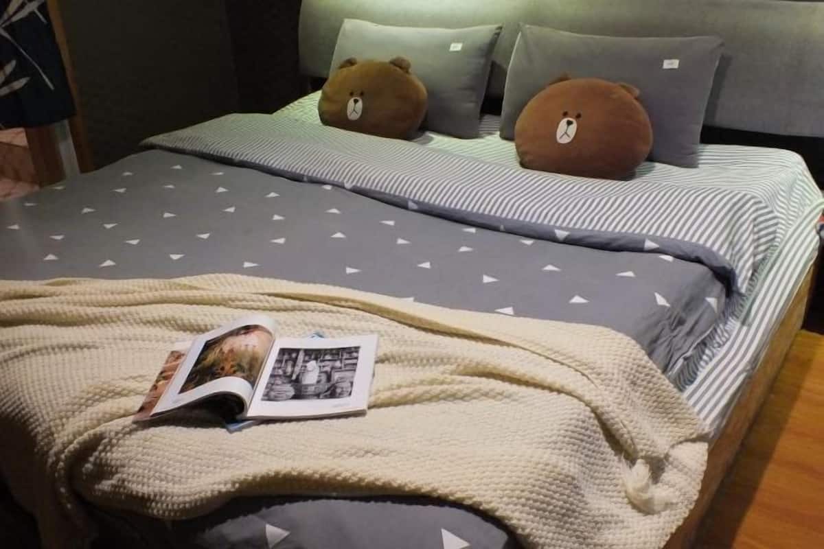A bed with a striped bedspread, two pillows, a blanket, and a magazine.