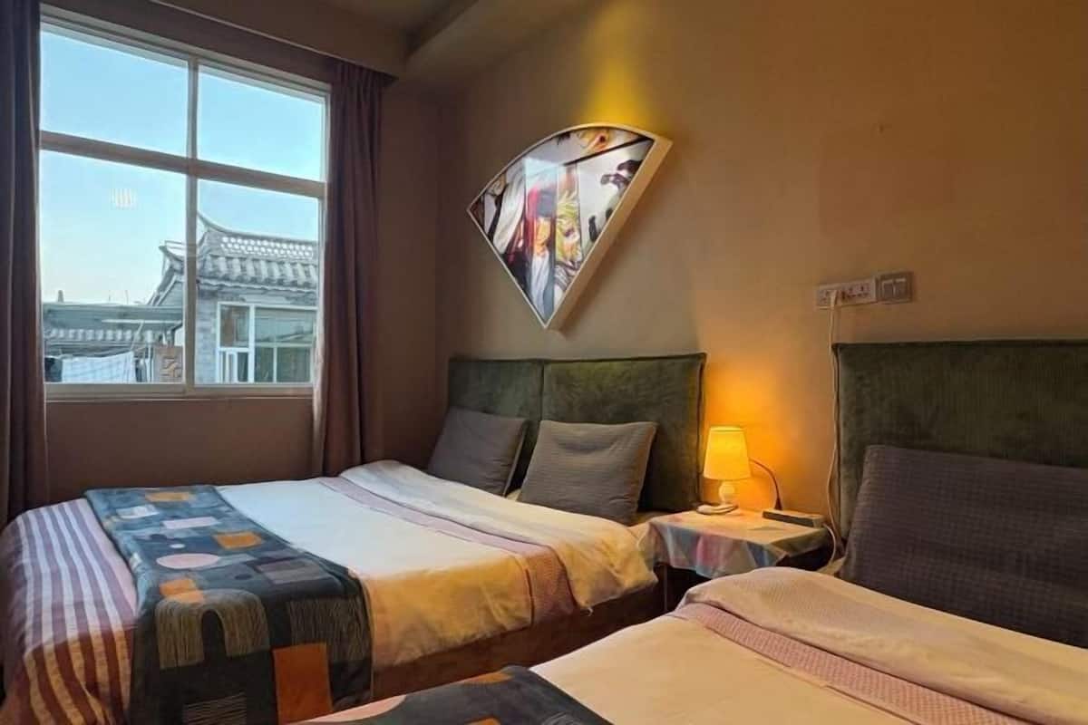 A hotel room with two beds, a nightstand with a lamp, and a wall-mounted artwork.