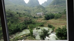 A view of terraced fields and a building in a hilly landscape.