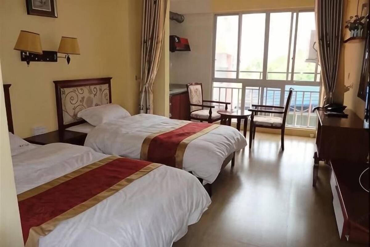 Een hotelkamer met twee bedden, een bureau, een stoel en een groot raam.
