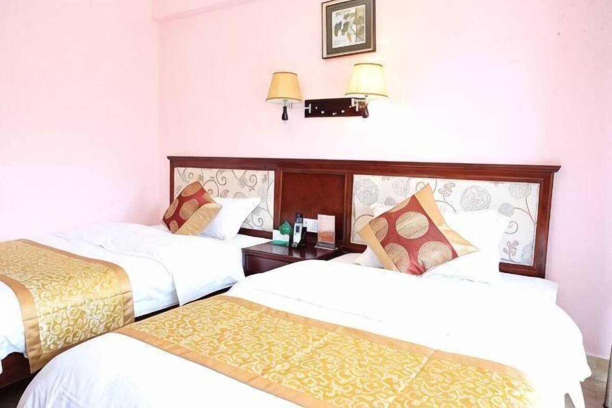 Een hotelkamer met twee bedden, een nachtkastje en een lamp aan de muur.