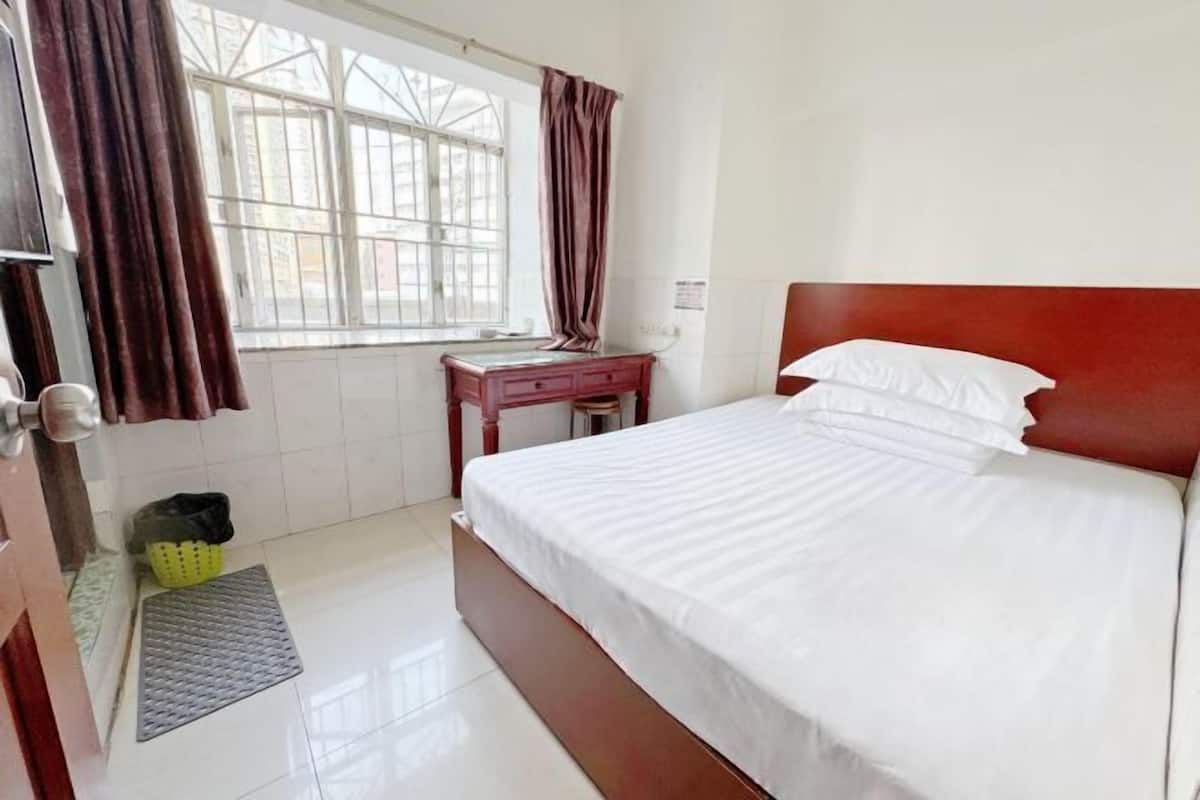 A bedroom with a bed, a nightstand, a window with curtains, and a door.