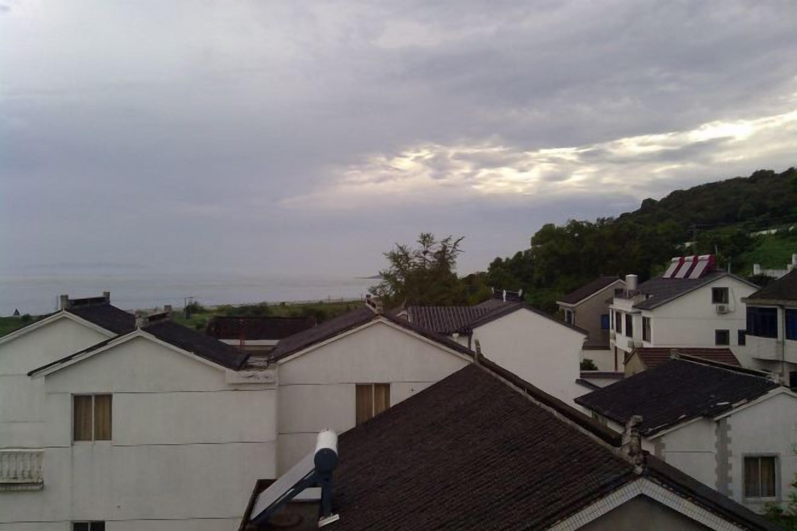 A residential area with houses, some with visible balconies, under a cloudy sky.