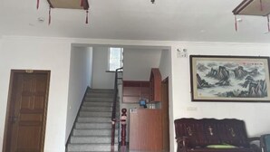Een hotel lobby met een trap, een houten receptiebalie, een groot schilderij in een lijst en een donkerbruine bank.