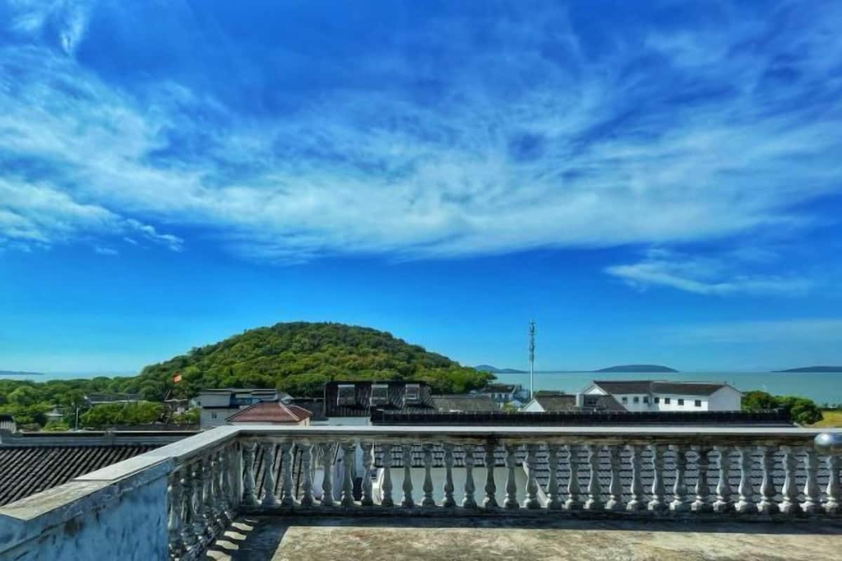 Küstensicht mit Balkon, ein Hügel im Hintergrund und klarer Himmel.