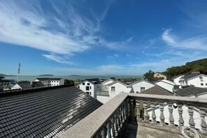 Une vue d’un quartier résidentiel avec des maisons blanches, un ciel bleu dégagé et des montagnes à l’horizon.