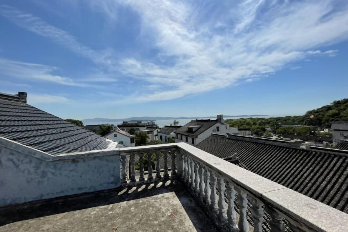 Une terrasse sur le toit, dotée d’une balustrade, qui offre une vue sur une ville aux bâtiments traditionnels et un ciel dégagé.