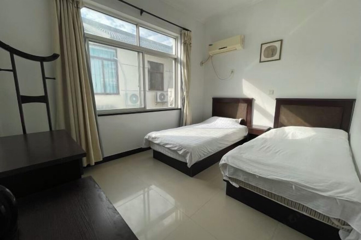 Une chambre d’hôtel avec deux lits simples, un bureau et une chaise.