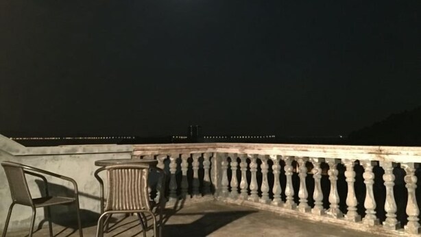 Een balkon met een hekwerk, twee stoelen en een tafel.