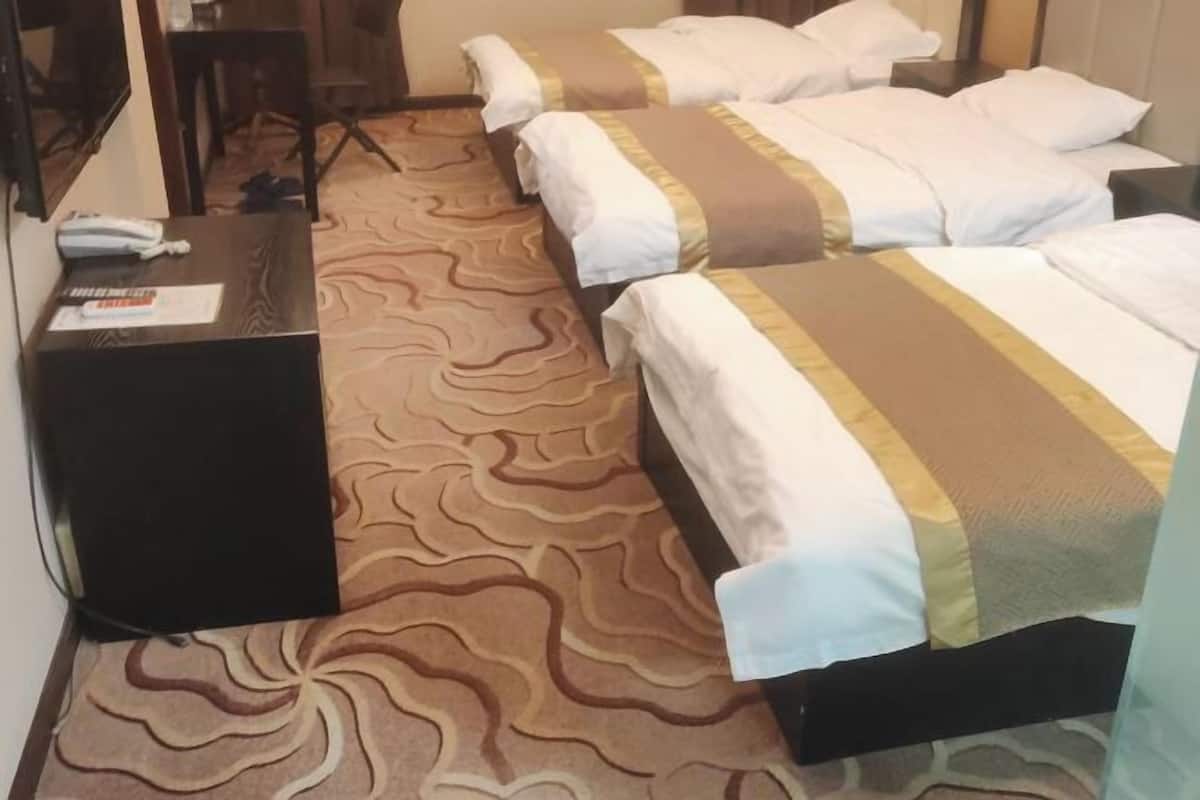 A hotel room with two beds, a desk, and a patterned carpet.