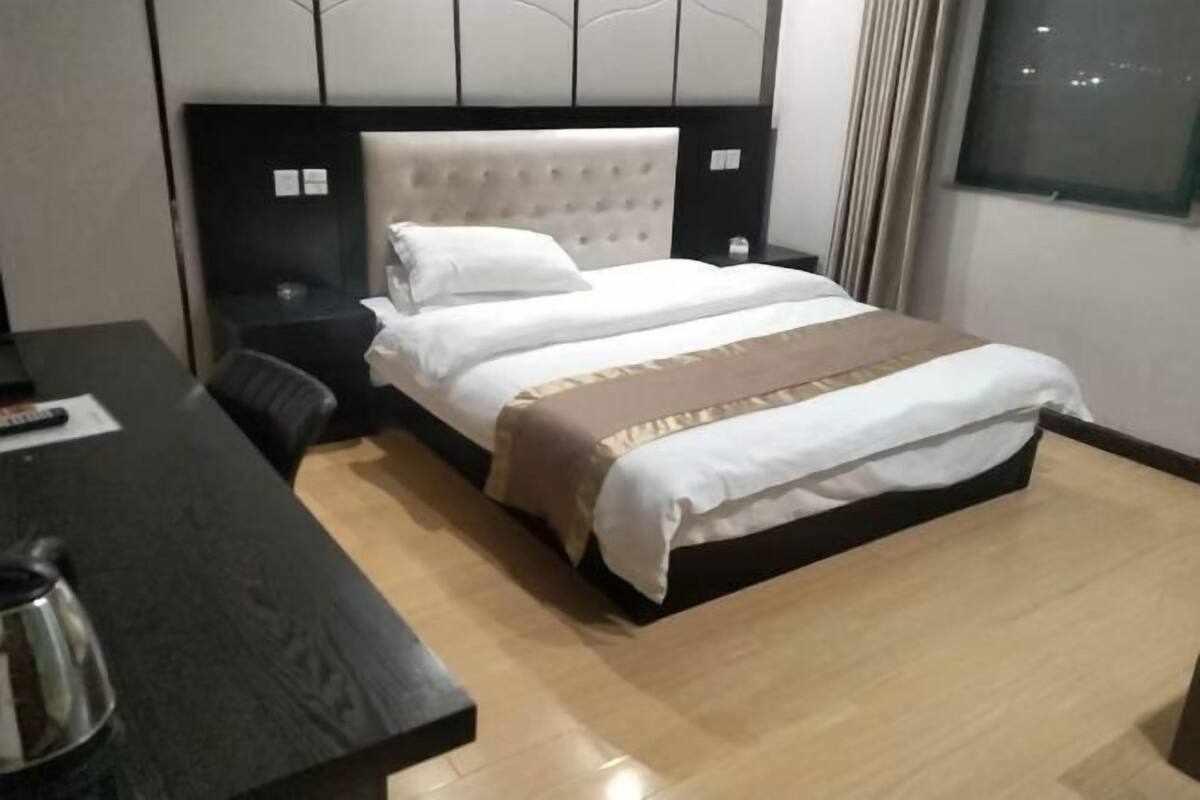 A hotel room with a bed, a desk, and a nightstand.
