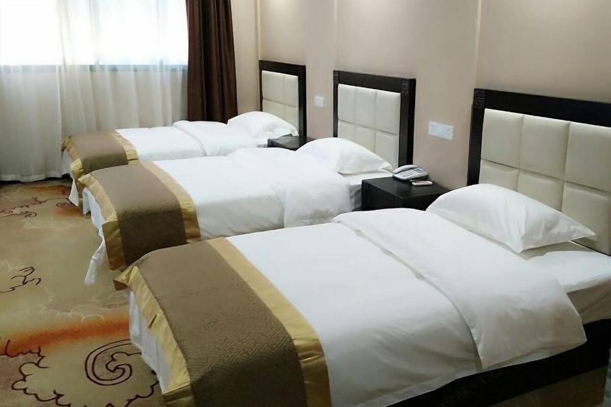 A hotel room with two beds, each with a headboard, a bedside table, and a telephone.