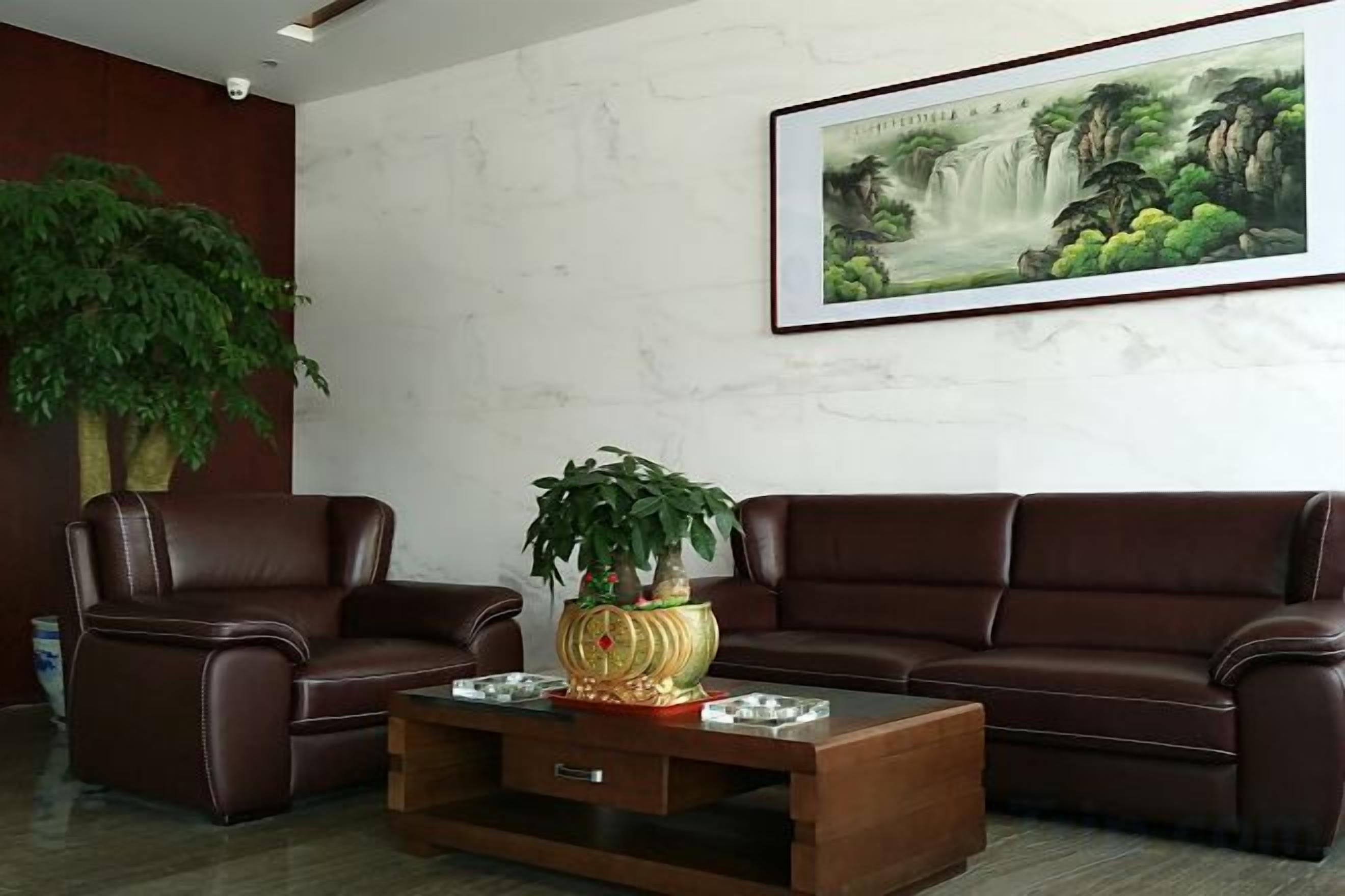 A living room with a brown leather sofa, a wooden coffee table with a plant, and a framed painting on the wall.