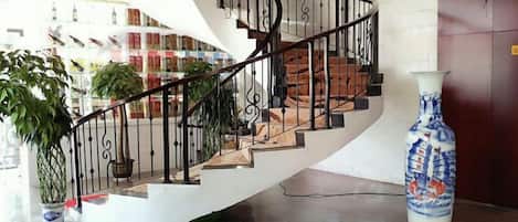 Una escalera de caracol con una pared blanca y un florero sobre una mesa.