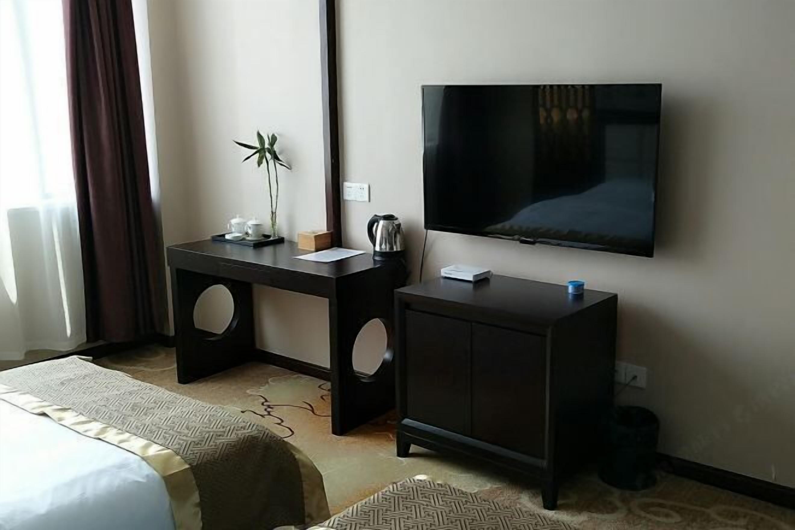 Ein Hotelzimmer mit zwei Betten, einem Schreibtisch, einem Flachbildfernseher, einer Kaffeemaschine und einem kleinen Schrank.