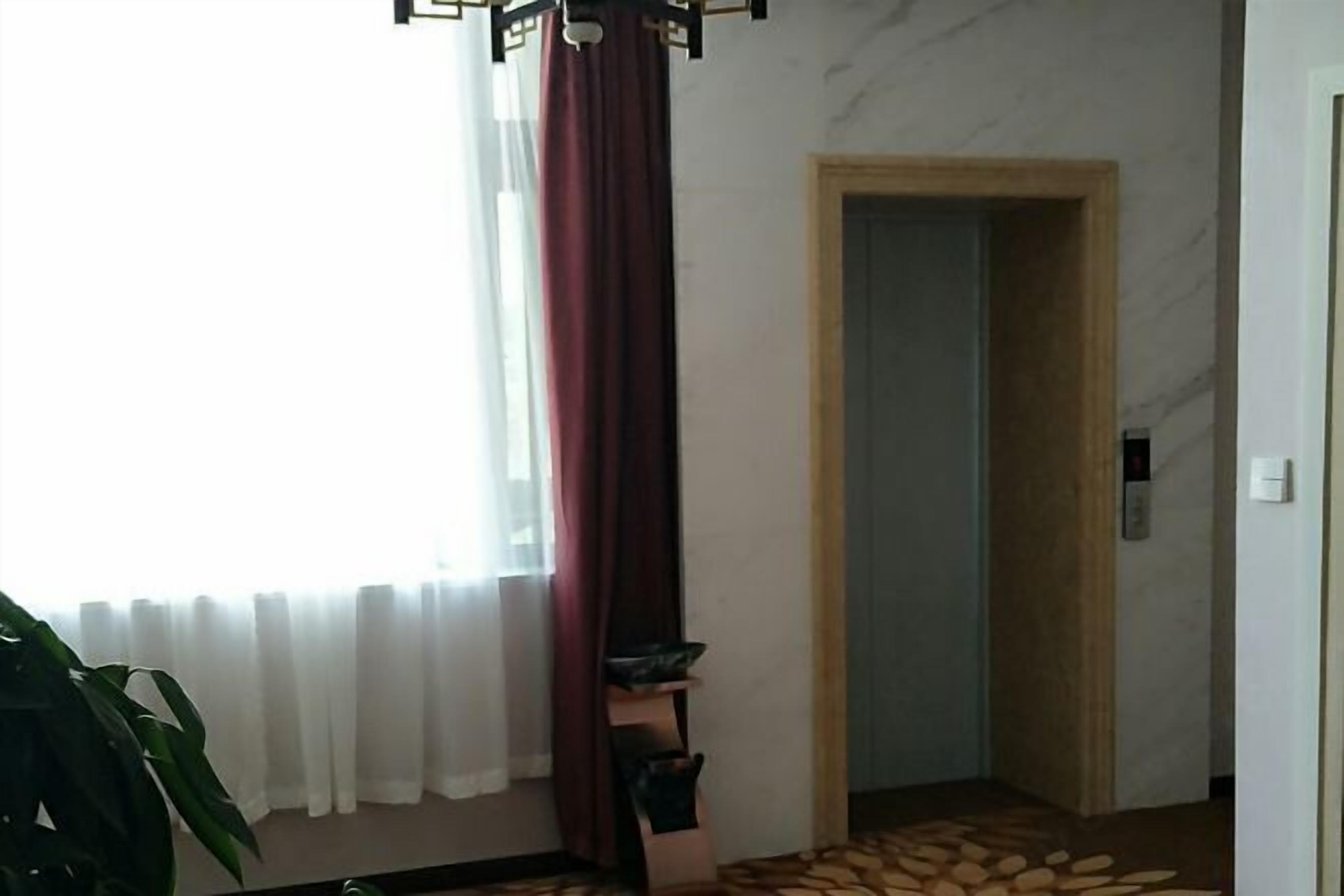A room with a large window, a plant, a door, and a patterned floor.