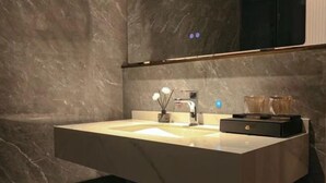 Une salle de bain moderne avec un grand lavabo en marbre, un miroir au-dessus et un petit meuble en dessous.