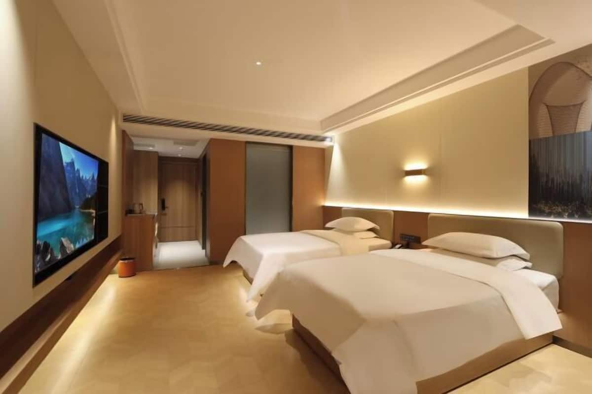 Ein Hotelzimmer mit zwei Betten, einem Fernseher und einem Gemälde an der Wand.