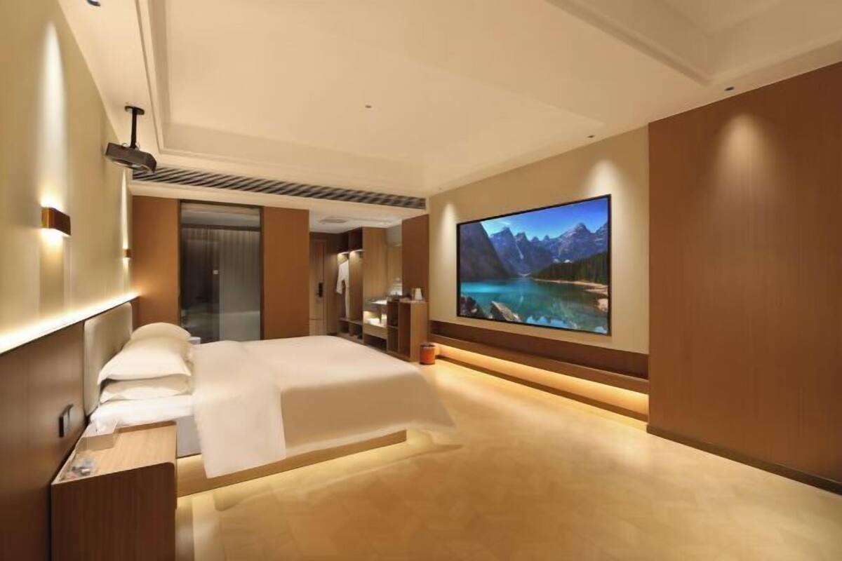 Ein modernes Hotelzimmer mit einem großen Bett, einem flachbildfernseher an der Wand und Holzboden.