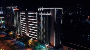 Un hôtel à plusieurs étages, doté d’un éclairage extérieur décoratif, d’un parking et d’un passage piéton.