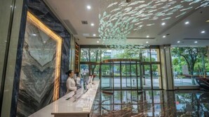 Un espace d’accueil doté d’un mur en marbre, d’une cloison en verre et d’un plafond orné de décorations suspendues.