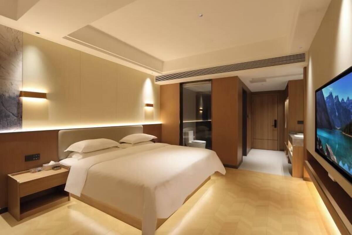 Ein modernes Hotelzimmer mit einem großen Bett, einem Fernseher und einem begehbaren Kleiderschrank.