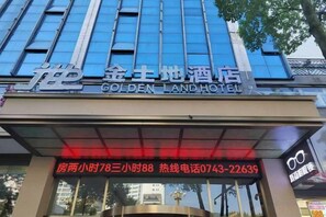 The exterior of the Golden Land Hotel with a clear sign displaying the hotel's name and contact information.