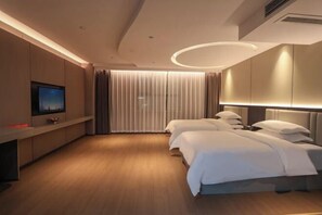 A modern hotel room with a wooden floor, a flat-screen TV mounted on the wall, a large bed with white bedding, and a ceiling light fixture. - Jintudi Hostel (Jishou)