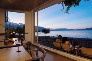 A dining area with a view of a lake and mountains, featuring wooden furniture and a glass partition. - Shanshui Qingju Inn (Dali City)