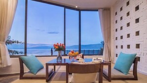 A room with a large window, two chairs, a table, and a vase with flowers. - Shanshui Qingju Inn (Dali City)