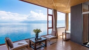 A balcony with a view of the sea, a wooden table, a chair, and a small side table. - Shanshui Qingju Inn (Dali City)