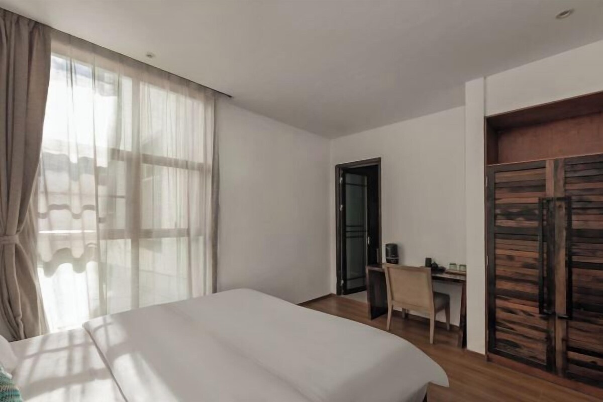 A hotel room with a bed, a desk, and a wardrobe.