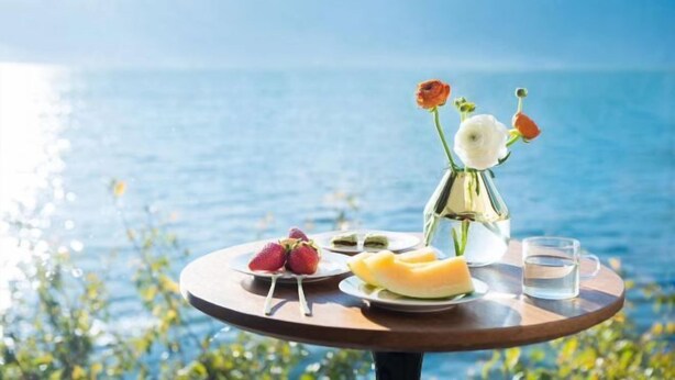 A table with food and a vase of flowers by a lake. - Shanshui Qingju Inn (Dali City)