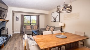 A modern living room with a wooden dining table, sofa, and a fireplace.
