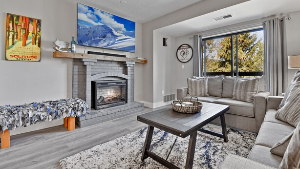 A living room with a fireplace, a sofa, a coffee table, and a large window with curtains.