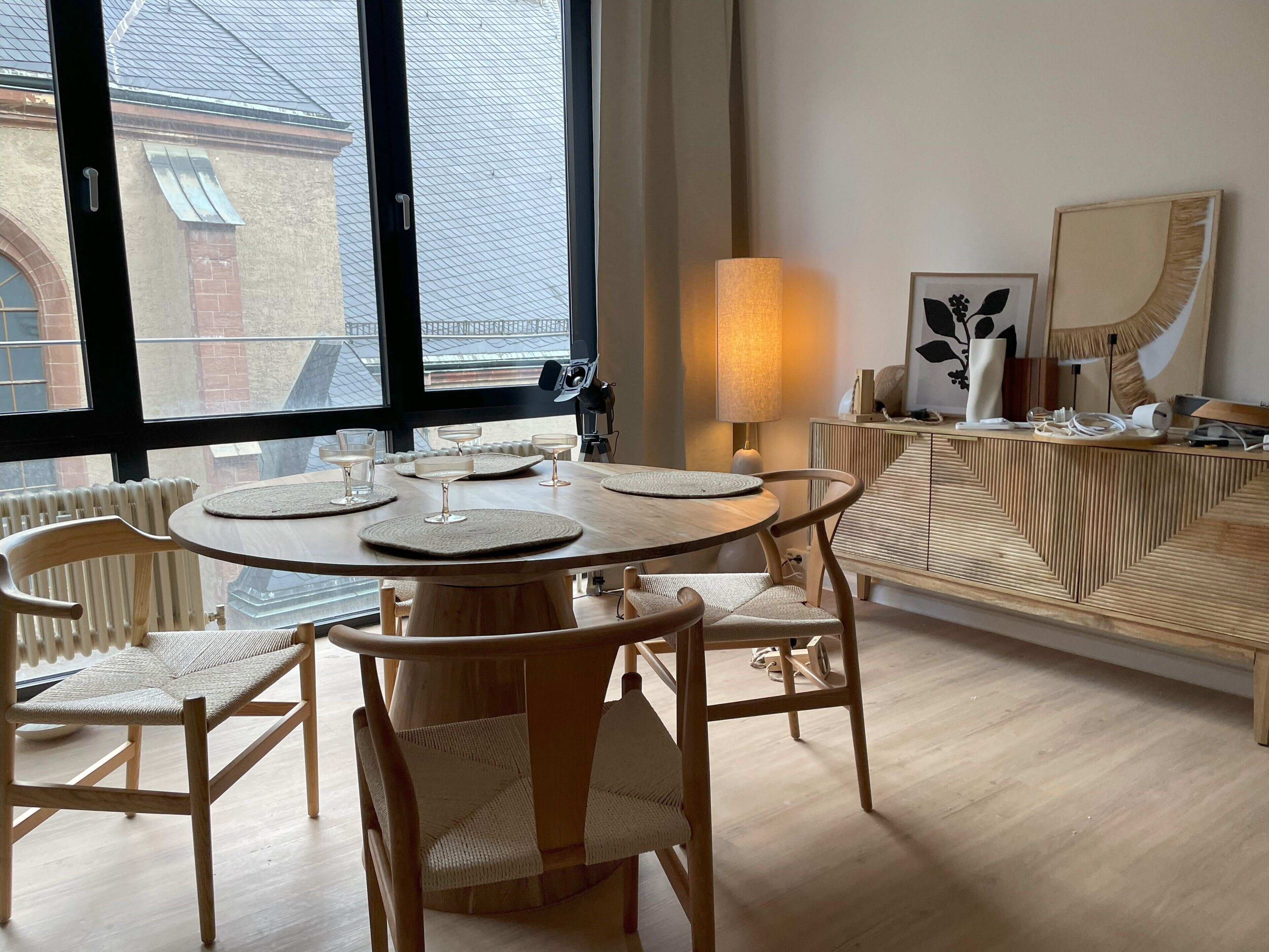 Een moderne eetruimte met een ronde houten tafel, twee stoelen en een bank.