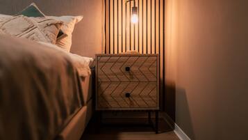 A neatly made bed with a patterned pillow and a bedside table with a light fixture.