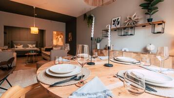 A dining area with a wooden table set for six, surrounded by chairs.