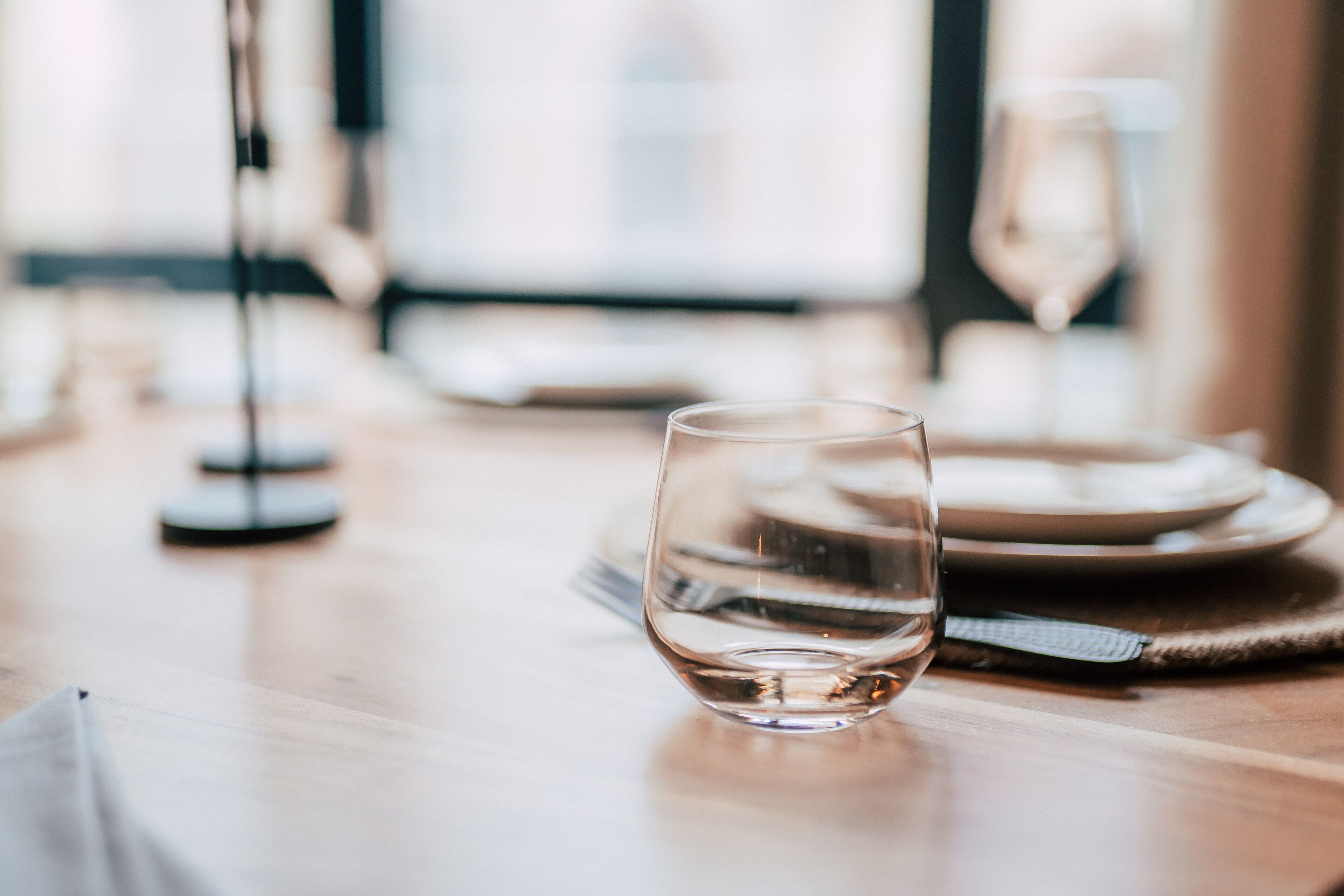 Une table à manger avec un verre d’eau, des assiettes et des couverts.
