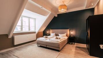 A modern bedroom with a large bed, a ceiling light fixture, a nightstand, and a radiator.