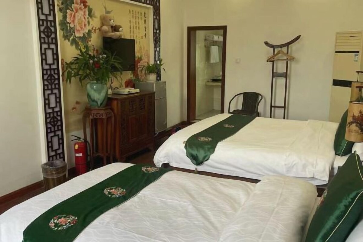 Ein Hotelzimmer mit zwei Betten, einem Schreibtisch, einem Stuhl, einem Spiegel und einer Wandverkleidung.