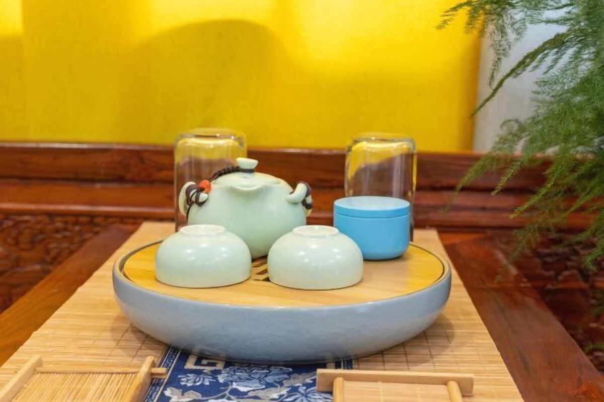 Um conjunto de chá tradicional sobre uma bandeja de madeira com um tapete azul e branco por baixo.