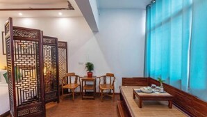 A traditional-style room with a wooden partition, a dining area with a table and chairs, and a large window with blue curtains. - Tongli Defu Caotang Boutique Hostel (Suzhou)