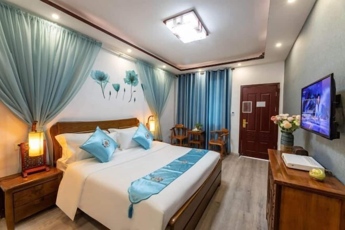 A hotel room with a bed, curtains, a TV, a desk, and a chair.